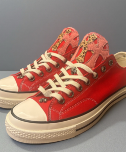 Red Converse shoes with pink and leopard print cross decorations.